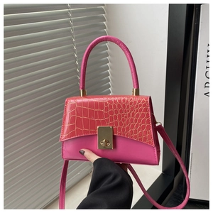 Detail der rosa Handtasche mit Krokodilleder-Prägung, goldenem Drehverschluss und Griff