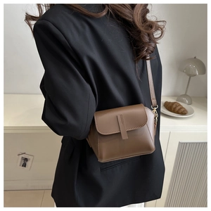 Minimalist dark brown soft leather crossbody bag styled in a cozy indoor setting