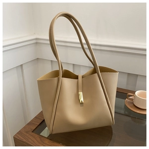 Detailed close-up of beige leather tote bag with elegant golden geometric buckle and strap