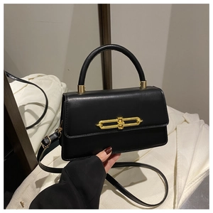 Detail of elegant black crossbody bag featuring a golden double-ring metal clasp and top handle