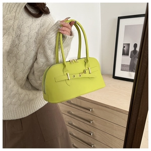Detail of neon green leather handbag with dual handles and decorative metal buckle