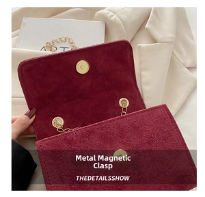 Close-up of burgundy suede flap bag with premium gold hardware buckle and chain strap
