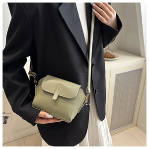 Sage green matte leather crossbody bag shown on a model in a minimalist blazer