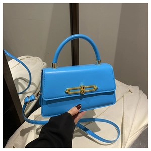 Detail of bright blue PU leather handbag showing the gold chain buckle and top handle