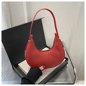 Close-up of a red crescent hobo bag with detailed woven leather texture and shoulder strap