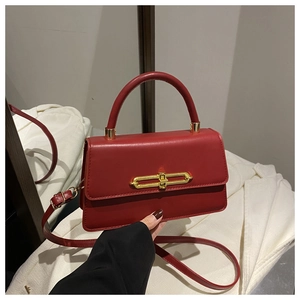 Detail of red leather crossbody bag featuring elegant gold rectangular metal buckle clasp