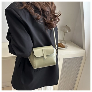 Sage green crossbody bag showing detailed side view worn on a model in a minimalist room