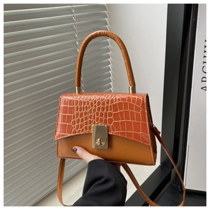 Detail der orange-braunen Handtasche mit Krokoprägung und goldenem Verschluss