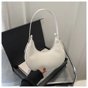 Close-up of white crescent underarm bag with woven texture in a black gift box