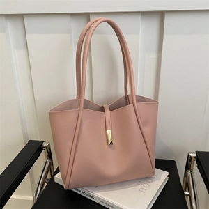 Pink minimalist faux leather tote bag with gold buckle on a black metal chair