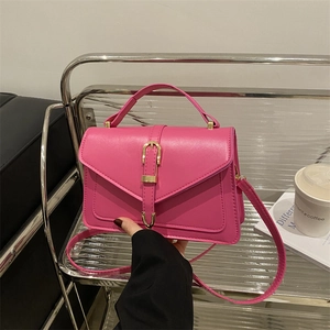 Pink crossbody bag with gold buckle on minimalist trolley with coffee cup and magazine