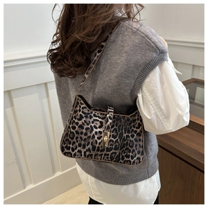 Rear view of a model wearing the leopard print shoulder bag with gold twist lock