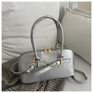Detail der silbernen Muschel-Handtasche mit matter Ledertextur und goldener Hardware-Optik