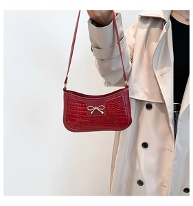 Détail du sac en cuir crocodile rouge foncé avec un fermoir nœud en métal doré