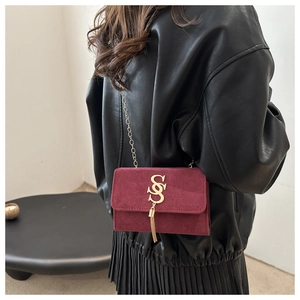 Detail of burgundy suede shoulder bag with gold SS logo and elegant tassel fringes