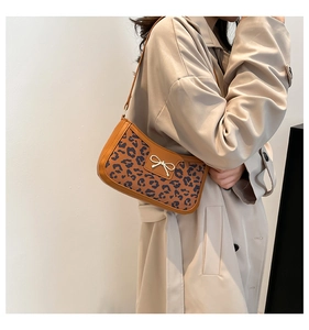 Détail du sac à bandoulière léopard avec bordure en cuir marron et nœud en métal argenté