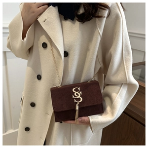 Close-up of matte suede crossbody bag with gold S-buckle and elegant chain strap
