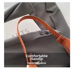 Detail of a brown suede crescent bag with a metallic zipper and elegant strap