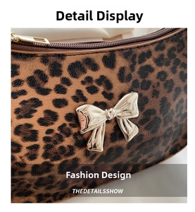 Detail view of leopard print texture with golden bow buckle and zipper on handbag