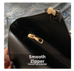 Detail shot of the internal gold metal zipper and inner pocket of the black leather tote bag