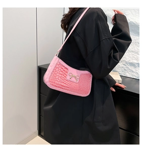 Détail du sac bandoulière en cuir croco rose avec une boucle en nœud métallique argenté