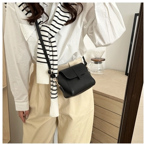 Minimalist black leather crossbody bag for women worn by a model in a modern home setting