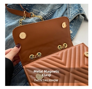 Close-up of golden magnetic clasps on brown V-quilted faux leather shoulder bag
