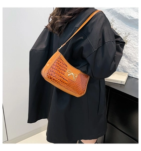 Détail du sac à bandoulière orange à motif crocodile et ornement de nœud doré élégant