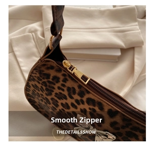 Close-up of leopard print crossbody bag featuring smooth gold metal zipper and faux fur texture