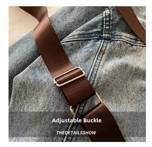 Detail of adjustable silver buckle and brown fabric strap on blue denim camera bag