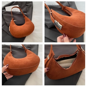 Detailed macro view of orange suede crescent bag with metal buckle and spacious interior