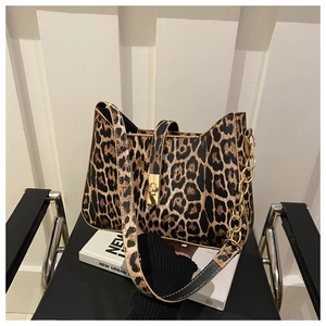 Detail of leopard print shoulder bag with gold twist lock and chain on a black leather chair