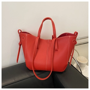 Detail of red lychee textured tote bag featuring contrast white stitching and leather knot