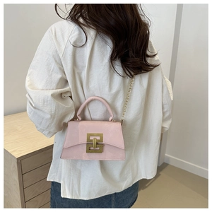 Detailed view of pink patent leather handbag with vintage gold buckle and chain strap