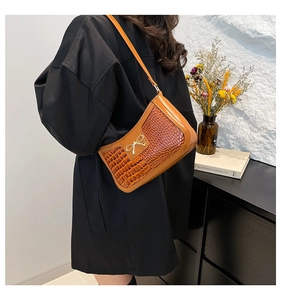 Détail d'un sac porté épaule marron caramel à motif crocodile avec nœud métallique