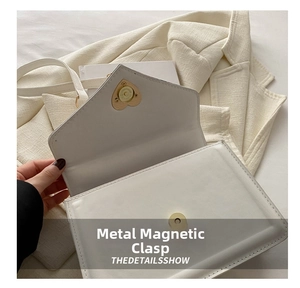 Détail d'un sac enveloppe en cuir PU blanc avec bouton pression magnétique doré en cœur