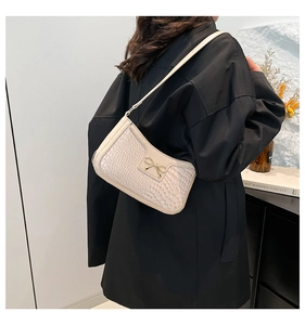 Détail du sac à bandoulière blanc cassé effet crocodile avec nœud doré métallique