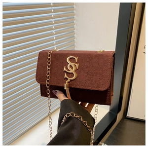 Detail of a brown suede bag featuring a gold S-letter logo and elegant tassel charm