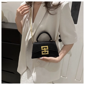 Detail of elegant black crossbody bag with gold lock and chain strap on a model