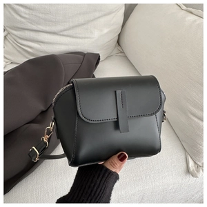 Detail of a black minimalist handbag with gold hardware and leather strap