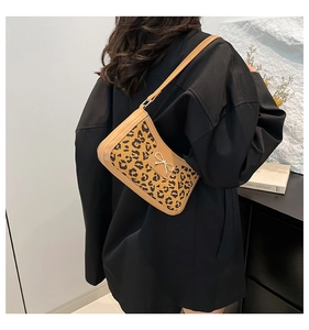 Détail du sac croissant imprimé léopard avec nœud en métal doré et bandoulière en cuir