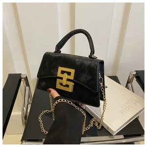 Detailed view of black textured leather bag featuring a gold geometric linked buckle and chain
