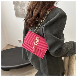 Detail of rose red quilted crossbody bag with gold chain strap and stylish tassel pendant