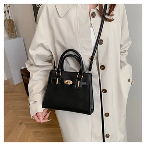 Detail of black matte leather Kelly bag with gold hardware worn by model
