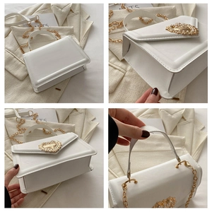 Détail d'un sac blanc avec boucle coeur dorée ornée de perles et bandoulière en chaîne dorée