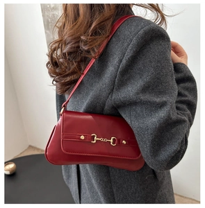 Sac bandoulière rouge rétro en similicuir avec boucle mors dorée sur un mannequin