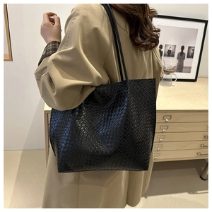 Detailed close-up of a black woven tote bag texture with minimalist interior background
