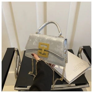 Detail of silver textured mini bag with golden metal lock and elegant chain strap