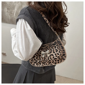 Detail of leopard print shoulder bag featuring a silver metal bow and matching zipper