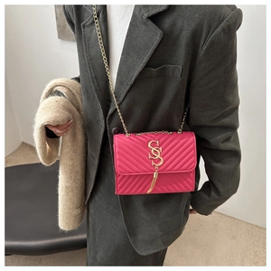 Detail of rose pink quilted crossbody bag with gold tassel and metal chain strap